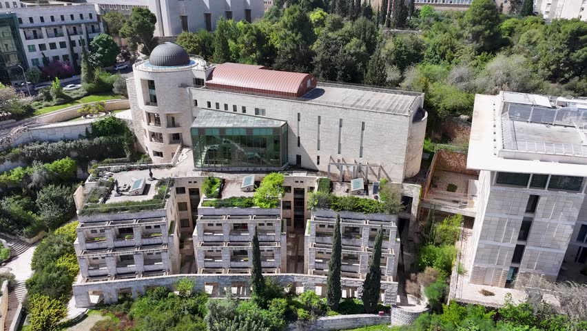 Modern architectural academic complex on Mount Scopus overlooking lush trees and the expansive Jerusalem city skyline.