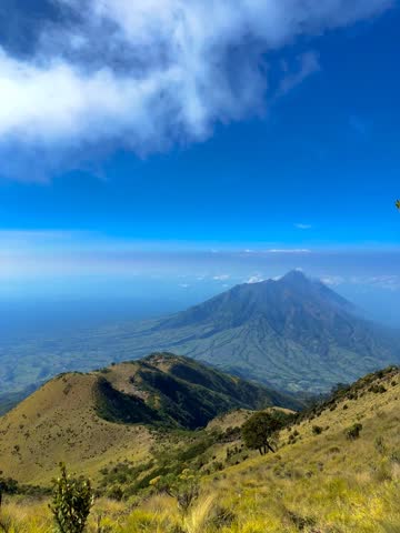 Scenic mountain landscape with lush green hills under clear, bright blue skies. Peaceful natural scenery featuring highlands, wilderness, countryside, sunny weather, and panoramic views.