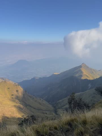 Scenic mountain landscape with lush green hills under clear, bright blue skies. Peaceful natural scenery featuring highlands, wilderness, countryside, sunny weather, and panoramic views.