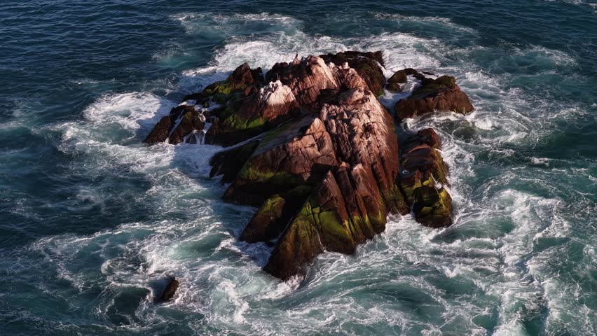 Top down aerial of waves crashing on La Palma rock in Cabo San Lucas, Mexico.