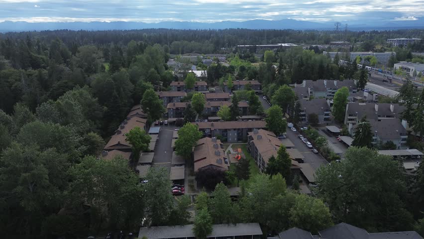 Dense evergreen trees frame Pete von Reichbauer Way S, where multi family complexes emerge amidst woodlands, capturing urban residential density alongside Cascade foothills in Federal Way, WA. USA