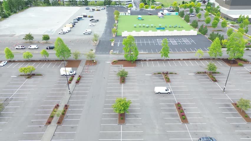 Open community gathering plazas adjoin Pete von Reichbauer Way South, featuring green synthetic lawn turf, patio tables, and open parking stalls in Federal Way, suburbs Seattle, Washington. USA