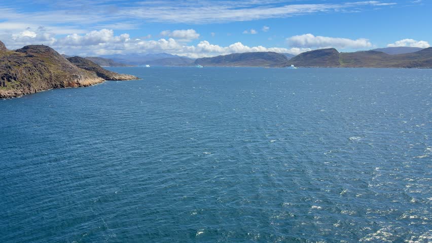 The fjords, mountains, and icebergs near the town of Qaqortoq, Greenland on a bright sunny day.