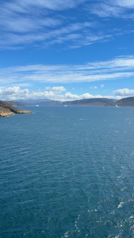 The fjords, mountains, and icebergs near the town of Qaqortoq, Greenland on a bright sunny day.