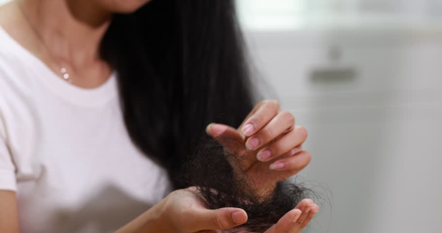 Young woman examining a large amount of hair in her hands, hair loss and concern