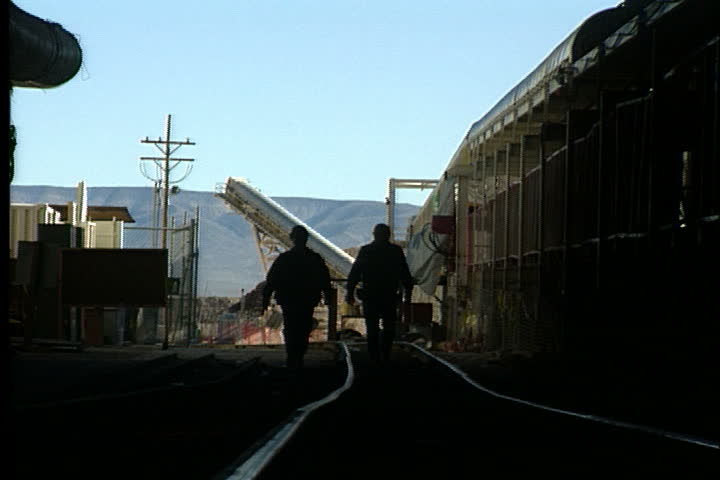 YUCCA MOUNTAIN, NEVADA - DECEMBER 02, 1996: Two workers in hard hats walk into dark Yucca Mountain tunnel.