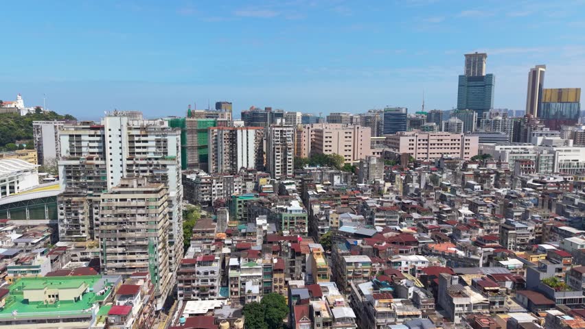 Right panning aerial view across Historic Centre of Macau featuring dense city blocks, residential towers, commercial buildings and modern skyline