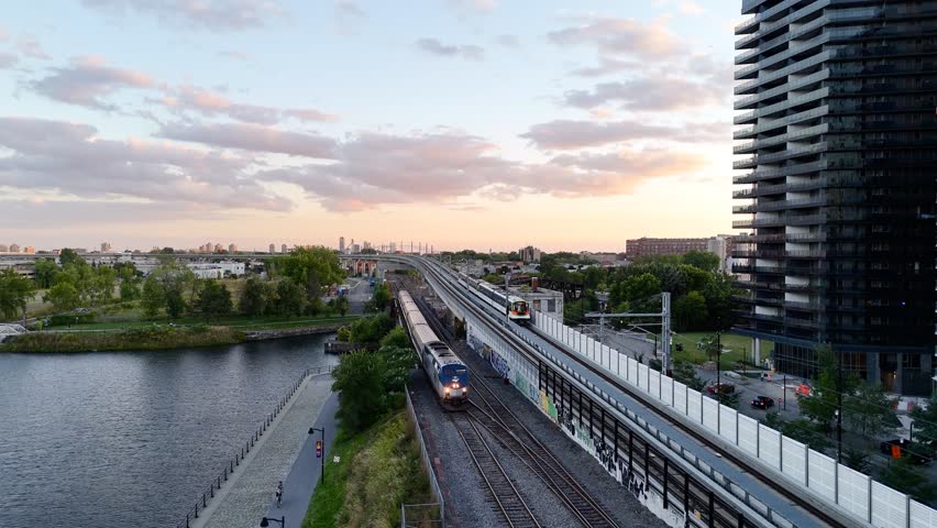 Passenger train passing through Griffintown, Montreal, Quebec, Canada at sunset with modern skyline. g.