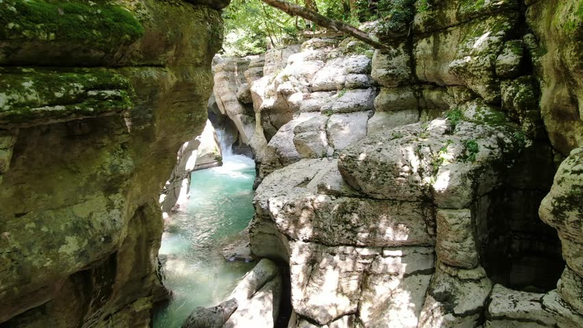Scenic view of the crystal-clear Khosta River flowing through the deep white rock canyon and lush green forest in Sochi, Russia.