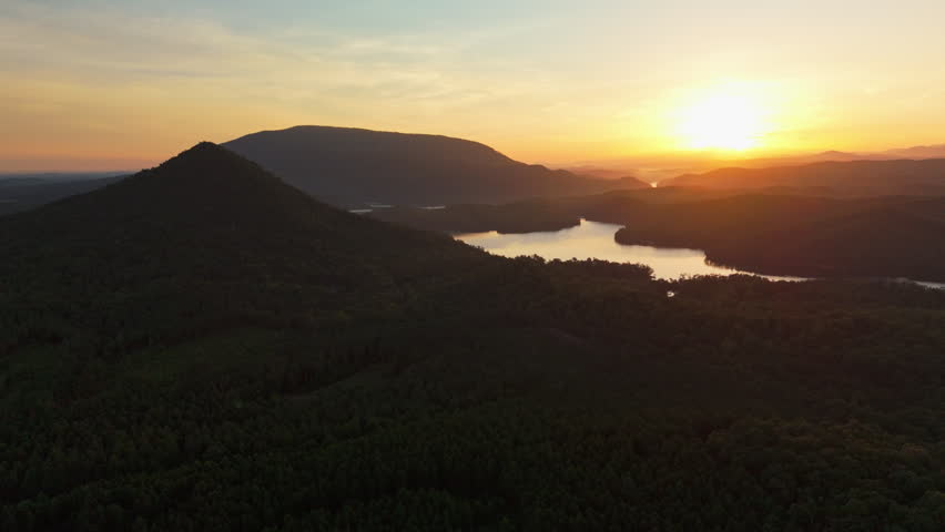 Sunrise light spreads across forested ridges and a lake in Tennessee.