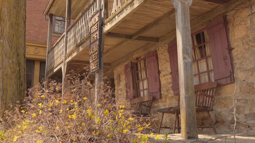 Historic stone Dowling House with wooden balcony and rustic chairs in Galena