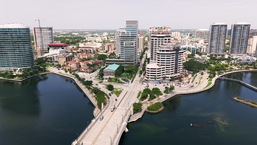 Bridge crossing West Palm Beach waterfront beside downtown skyline, aerial medium orbit above Royal Park Bridge and Flagler drive