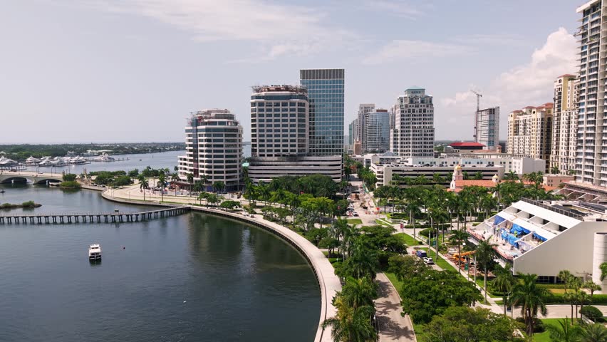 West Palm Beach waterfront skyline with palm lined promenade and marina, aerial establishing along Flagler Drive, background for real estate promos