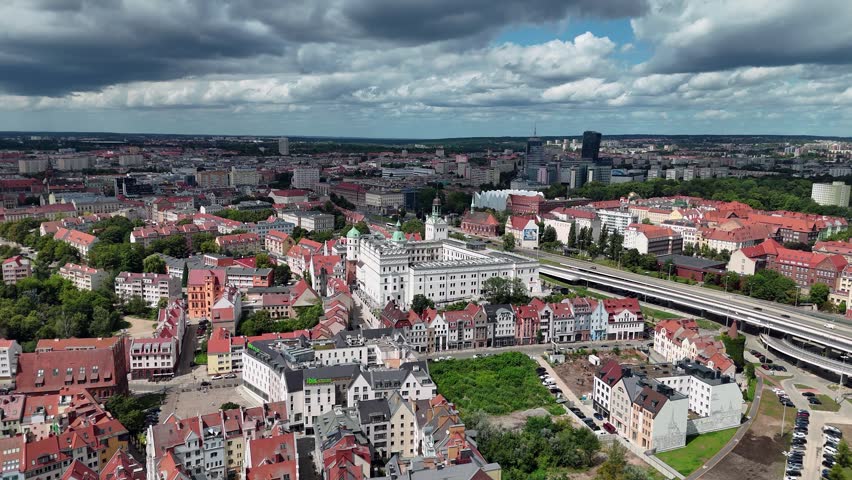 A high angle aerial shot of the historic Pomeranian Dukes Castle and surrounding old town architecture in Szczecin, Poland, under a dramatic cloudy sky.