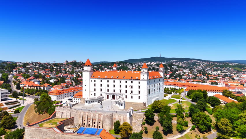 Footage around the hill with Bratislava Castle and its beautiful territory. Cityscape of low-rise houses at backdrop. Sunny day in the capital of Slovakia.