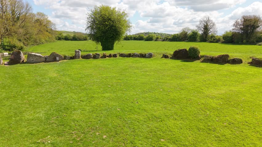 Ancient stone circle set in a green field under a partly cloudy sky in Ireland
