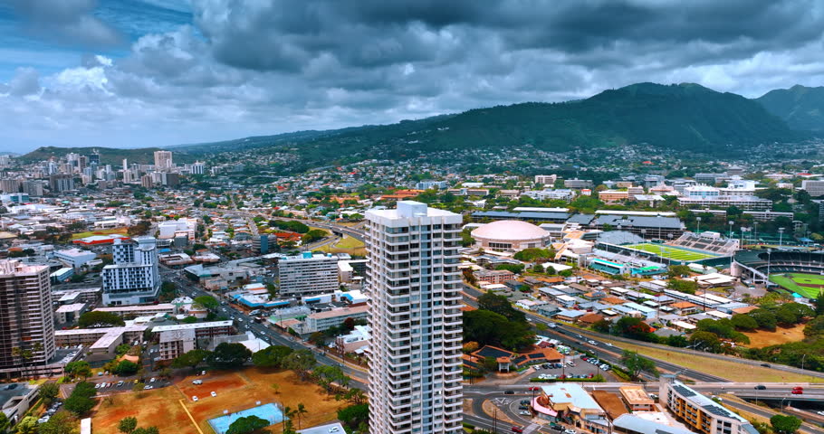 Flying away from the high-rise building in the scenery of Honolulu, Hawaii, USA. View on the city under the overcast sky.