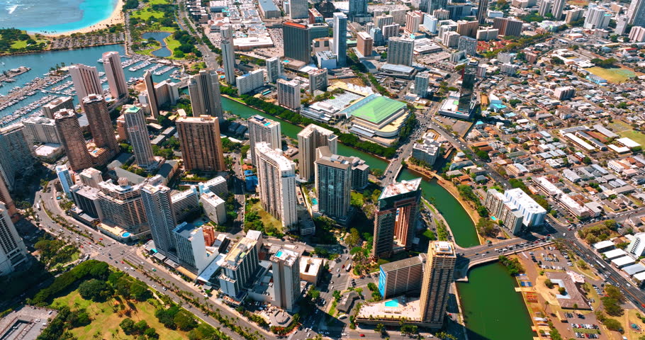 Flight over Waikiki resort area separated by the Ala Wai Canal. Beautiful cityscape of Honolulu, Hawaii, USA on sunny day.