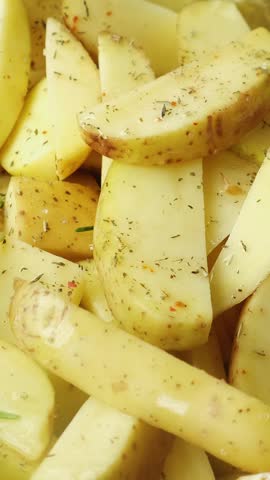 Vertical video. Cooking. Hand adding rosemary to potatoes wedges for baking