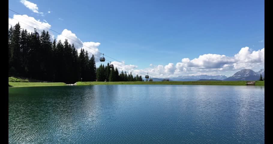 A stunning mountain landscape featuring a clear, blue-green artificial lake in the foreground.