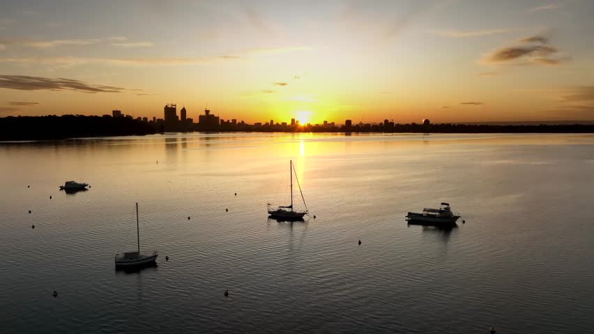 Aerial view of Matilda Bay at sunset with sailboats on the water and the Perth skyline in the distance in Crawley, Western Australia, Australia.