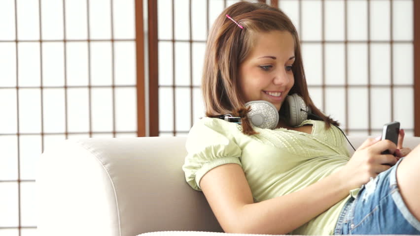 Girl with headphones sitting on couch with phone
