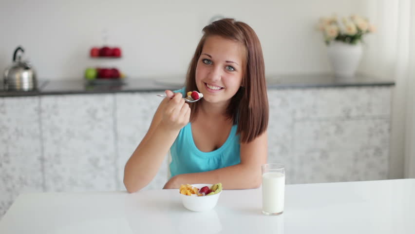 Sweet girl eating yogurt with fruits
