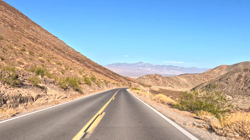 Dashcam View of a Highway Passing Through Arid Desert Mountain Canyon In Death Valley