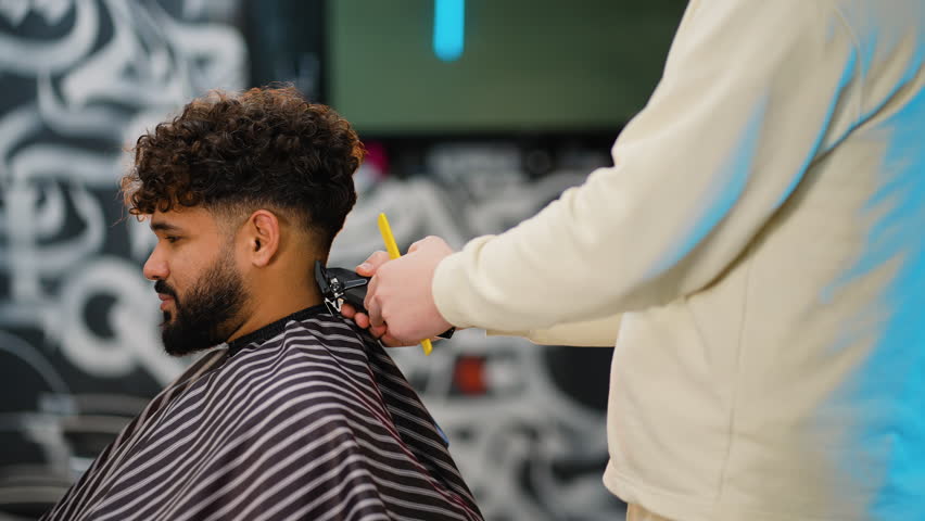Professional barber giving haircut with electric clipper