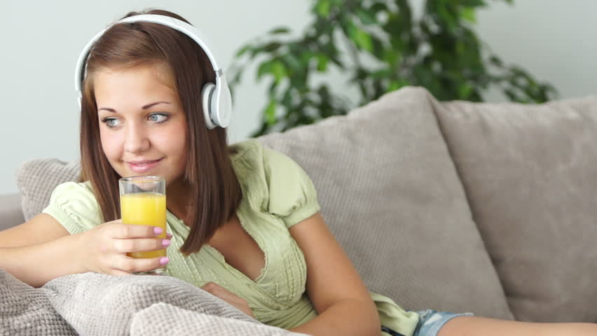 Teenager listening to music and drinking orange juice
