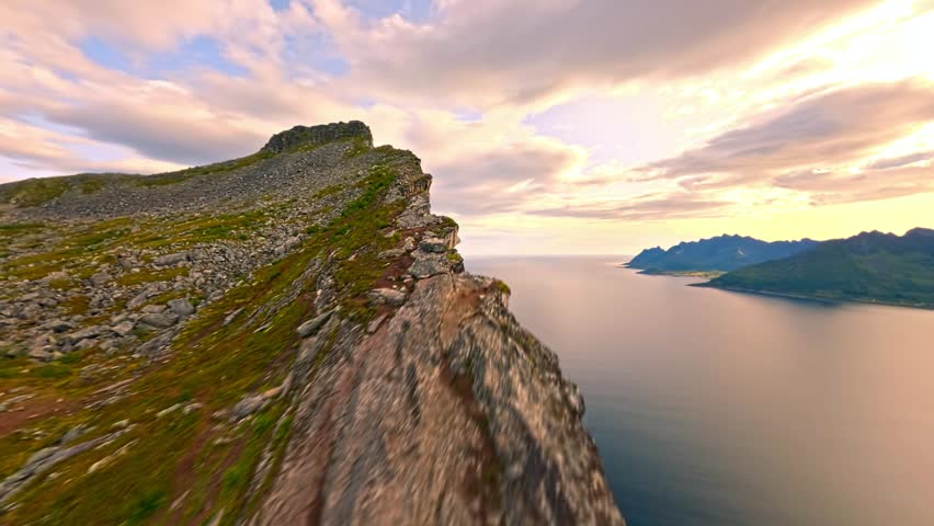 Drone Flying Along the Edge of a Cloudy Mountain Over a Blue Lake