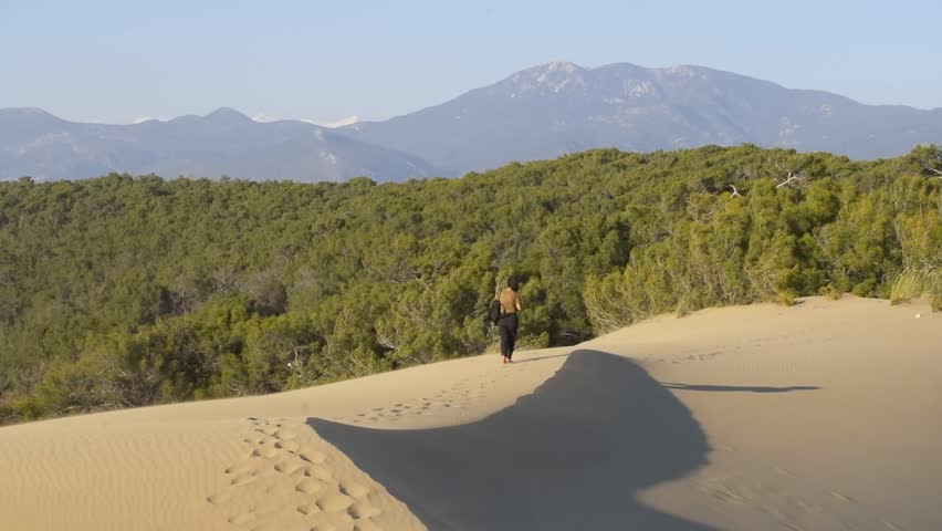 Young woman walking on sand dune in the desert enjoying freedom and adventure in Patara beach, Turkey
