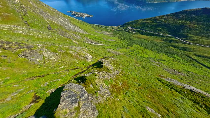 Drone Flying From a Mountain Top Over a Beautiful Blue Lake and Green Plateau