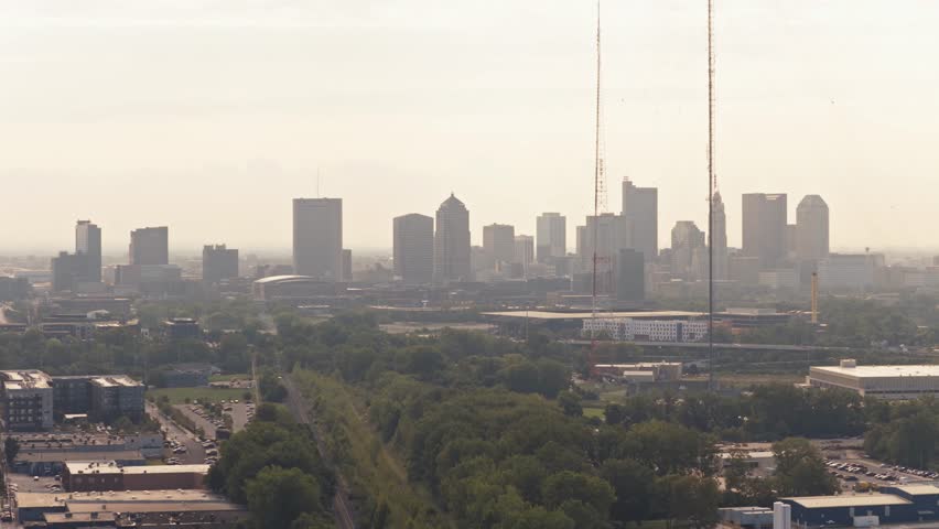 Skyscrapers and high-rise towers of Columbus, OH capital of central Ohio with long-lens tight view from drone helicopter aerial looking east towards city center infrastructure on sunny warm summer day