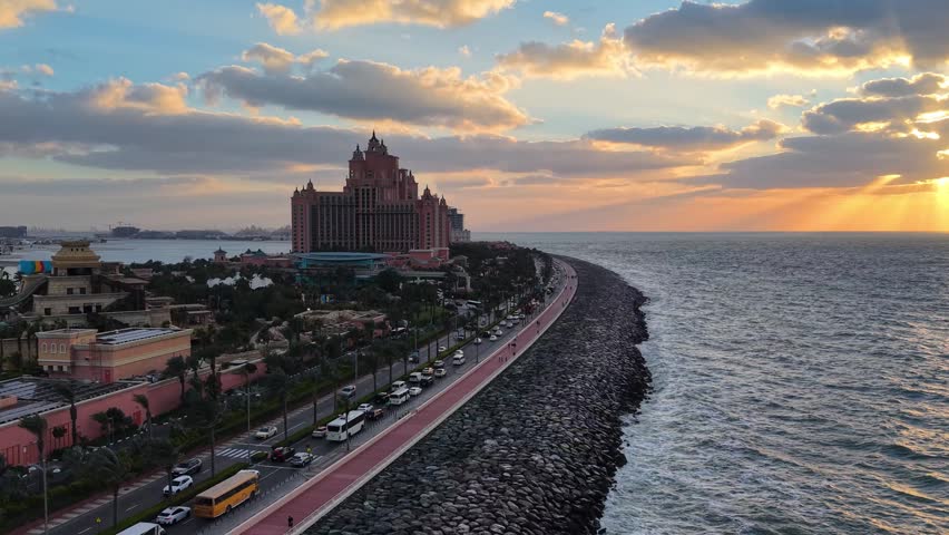 Palm Jumeirah artificial island in Dubai, United Arab Emirates. Features luxury resorts, pristine beachfronts, coastal waves hitting the breakwater barrier, and sparkling turquoise Persian Gulf waters.