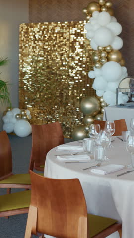 Elegant banquet table with gold and white balloon decor, sequined backdrop, and modern chairs