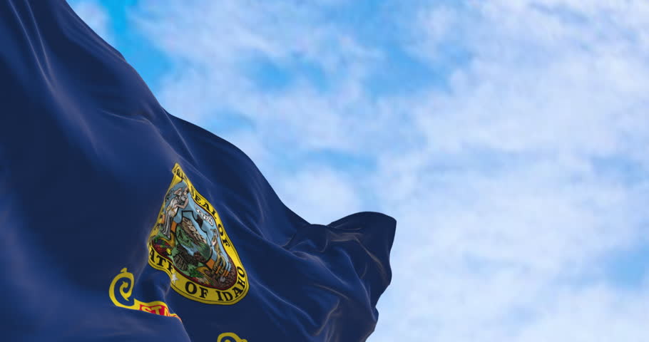 Close-up of the Idaho state flag waving in the wind on a clear day. Seamless 3d render animation. Slow motion loop. Selective focus