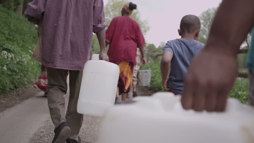 A family group of African villagers travel together with many containers, to find water to bring back to their village. In slow motion. Royalty-Free Stock Footage #4150222
