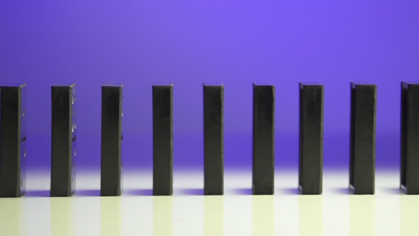 row of dominoes with one falling over on white background