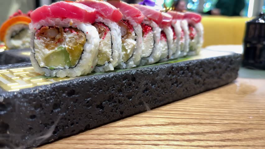Premium sushi roll topped with fresh tuna served on a black stone plate in a Japanese restaurant