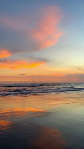 Stunning colorful sunset over the ocean with gentle waves crashing onto the sandy beach