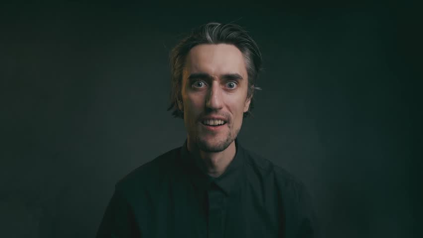 shocked surprised touch the viewer Young adult man with varied facial expressions and hand gestures in close-up against black background, emphasizing communication and intense emotion