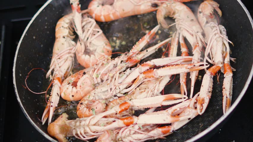 Top Down View of Fresh Garlic being Dropped on Fresh Langoustines Cooking in Hot Pan. Shellfish Seafood being Cooked Outdoors in Slow Motion. Norway Lobster.