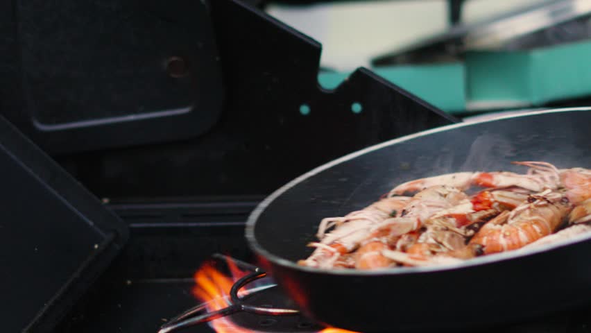 Fresh Langoustines Being Flipped in Hot Pan with Burning Flames from Gas Stove Below. Shellfish Seafood being Cooked Outdoors in Slow Motion. Norway Lobster.