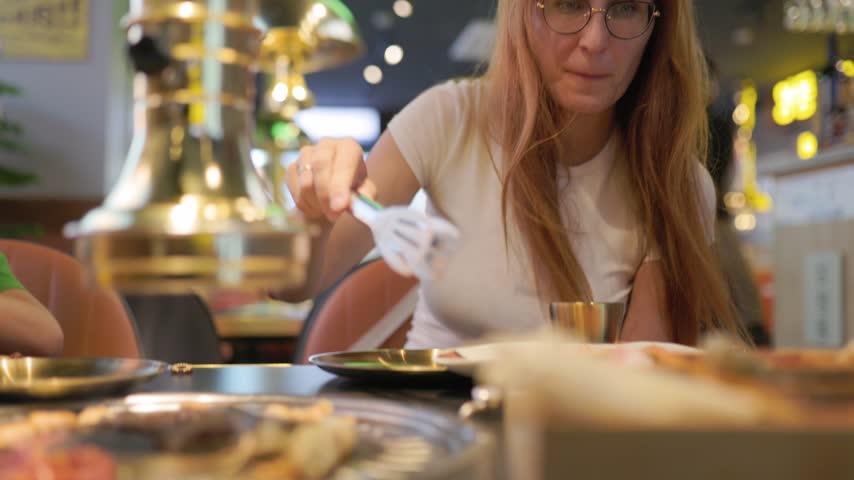 Woman enjoying korean barbecue grill in asian restaurant