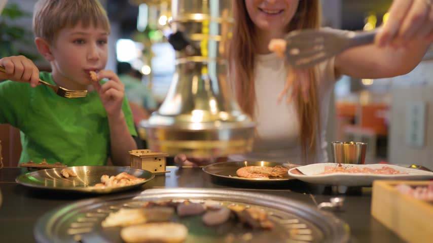 Mother and son enjoying korean barbecue restaurant dinner