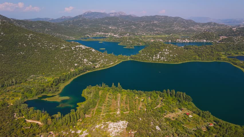 Panoramic aerial view of the vibrant blue Bacina Lakes surrounded by green karst hills near Ploce, Croatia