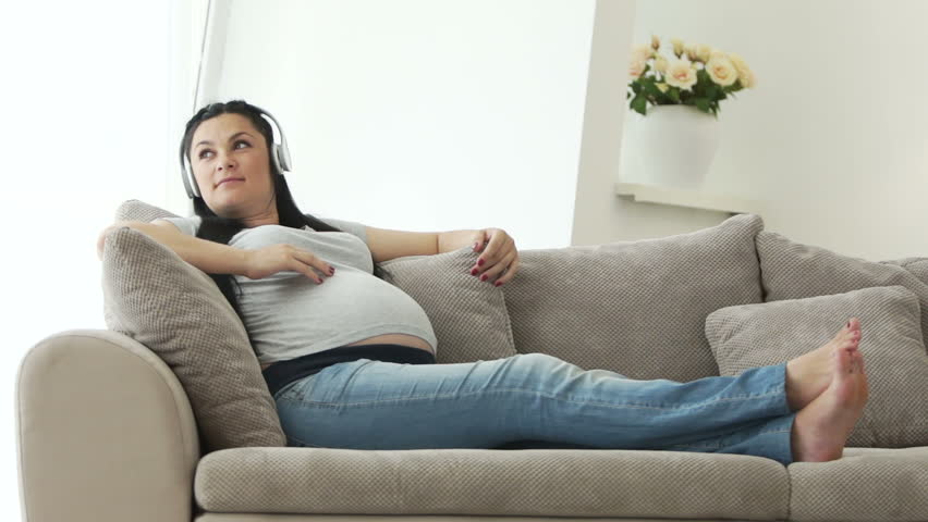 Pregnant woman listening to music and stroking tummy

