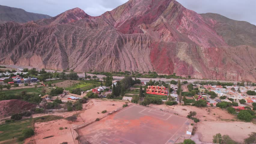 4K drone aerial view of a football field in Purmamarca, Jujuy, Argentina. A unique sports ground surrounded by the colorful Andean mountains and the iconic landscapes of the Quebrada de Humahuaca.