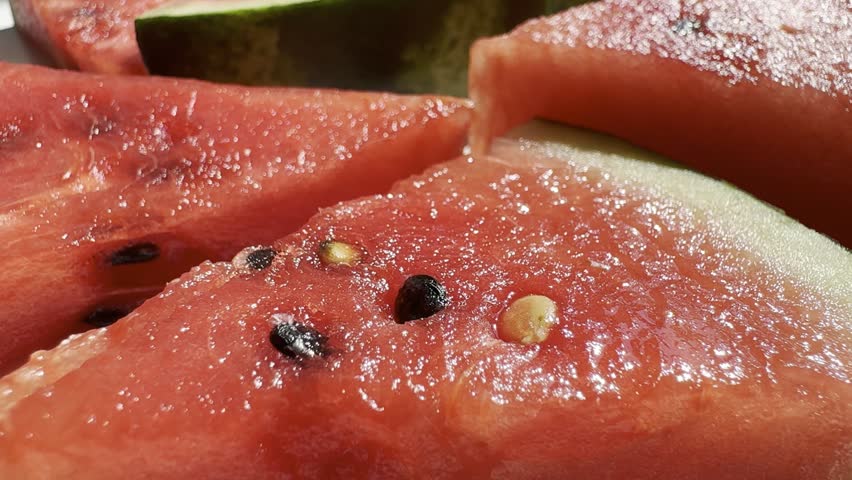 Watermelon slices on a white table under natural sunlight. Sliced watermelon.